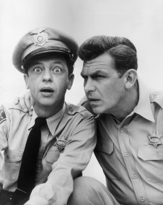 circa 1965: American actor Don Knotts looks at the camera with a surprised expression, as Andy Griffith holds his hand on his shoulder, posing in character as Deputy Barney Fife and Sheriff Andy Taylor in a publicity still for the television series, 'The Andy Griffith Show'. (Photo by Hulton Archive/Getty Images)